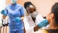 Dental resident examines patient in chair
